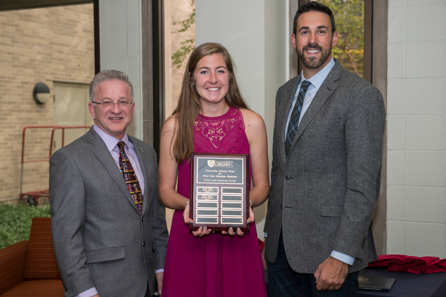 Library Director Ken Gibson, Molly Onders, and Dr. Marcus Mescher smiling together as Molly holds her award